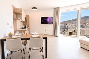 Un comedor moderno con una mesa grande, dos sillas y un televisor montado en la pared.