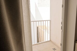 A narrow corridor with a white door leading to a balcony with a white railing. - Modern Seaside Apart in Marsalforn - 6D, Marsalforn Iz-Zebbug Gozo, Malta (Marsalforn Iz-Zebbug Gozo)