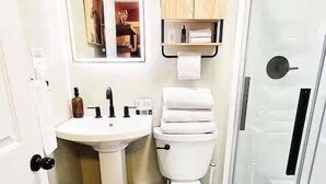 Et badeværelse med vask, toilet og bruser.