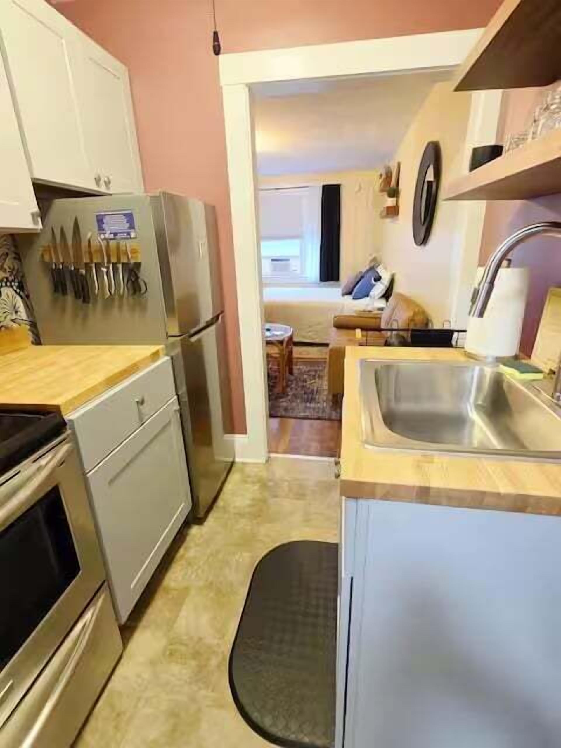 A compact kitchen with a refrigerator, stove, sink, and a small dining area.