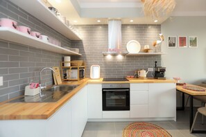 Una cucina moderna con mobili bianchi, forno integrato, microonde e lavello.