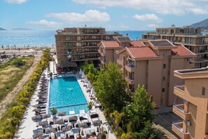 Un resort con piscina, lettini e vista sul mare.