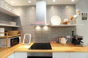 A kitchen with a microwave, toaster, and coffee maker on the counter, a sink, and a brick wall backsplash. - Cherry Studio Palm Radhime, Vlore, Albania (Vlore)