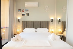 A hotel room with a bed, two bedside lamps, a wall-mounted air conditioner, and a mirror. - Cherry Studio Palm Radhime, Vlore, Albania (Vlore)