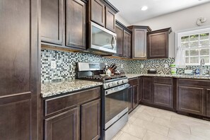 A modern kitchen with dark wood cabinets, a stainless steel range, and a tiled backsplash.