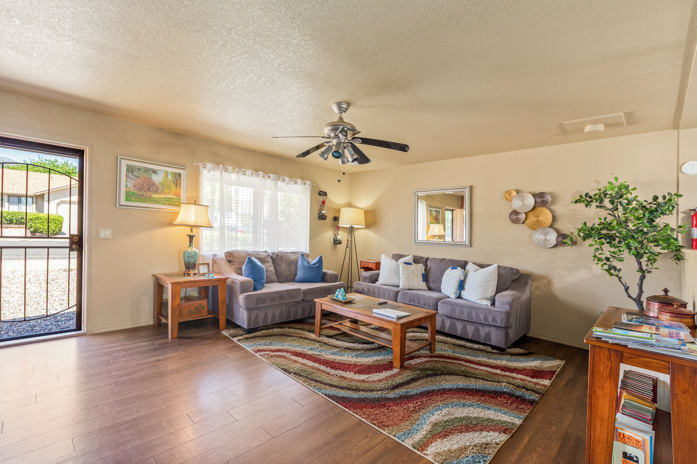 A living room with a ceiling fan, two sofas, a coffee table, and a rug.