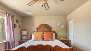 Une chambre à coucher avec un lit en bois, une table de chevet, une lampe et des miroirs décoratifs sur les murs.