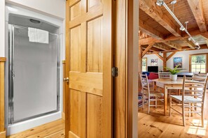 A wooden door leading to a room with a dining table, chairs, and a television. - The Barn on the Bagaduce - NEW! Waterfront (Sedgwick)