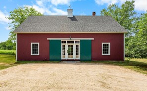 A single-story building with a red exterior and green trim, a front door, and a small window on each side. - The Barn on the Bagaduce - NEW! Waterfront (Sedgwick)