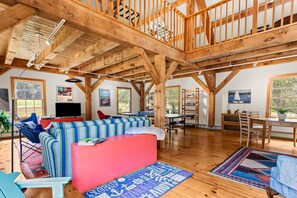 A spacious living area with a wooden ceiling, a sofa, a dining table, and a view of the outdoors. - The Barn on the Bagaduce - NEW! Waterfront (Sedgwick)