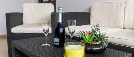 A wicker table with a bottle, glasses, a candle, and a potted plant.