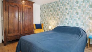 A bedroom with a bed, a wardrobe, and a patterned wall. - Gîtes de France® - Between the Golf Course and the Sea (DIEPPE)