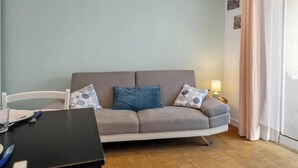 A living room with a sofa, a table, and a lamp. - Gîtes de France® - Between the Golf Course and the Sea (DIEPPE)
