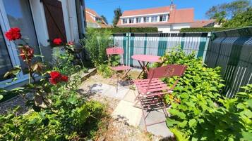 A patio with outdoor furniture, a garden with plants and flowers, and a house in the background.