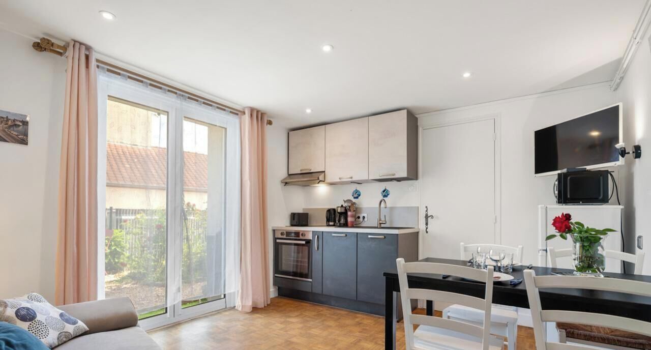 A compact kitchen with a dining area, a TV, and a sliding glass door to the outside.