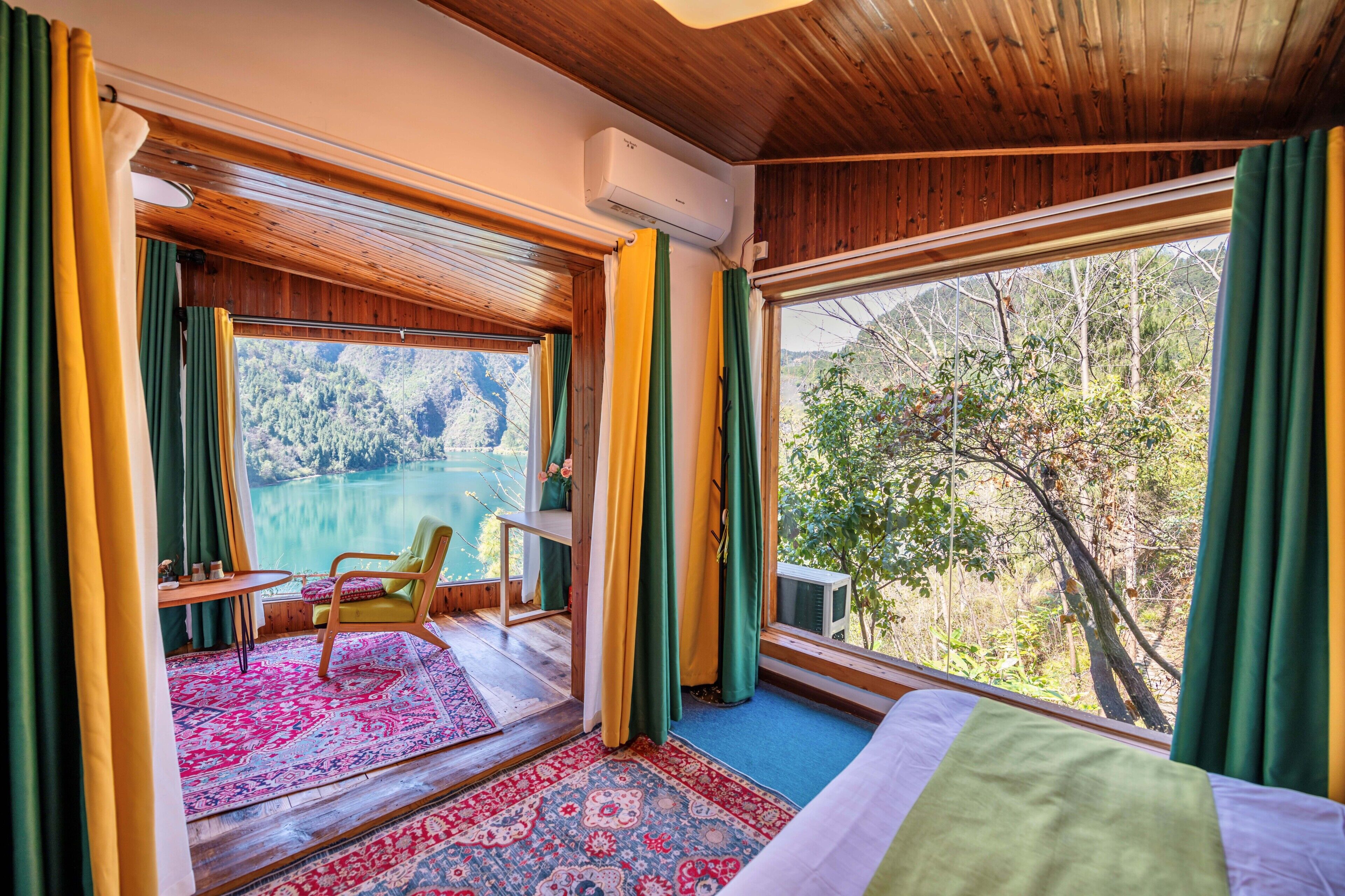 A room with a large window, a bed, a chair, and a small table.