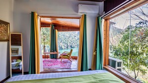 Una camera da letto con un letto, vista su un balcone con tavolo e sedia, e una finestra con tende.