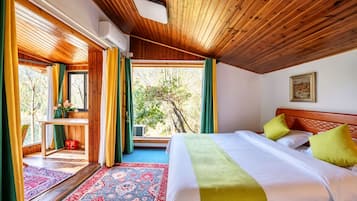 Un dormitorio con una cama grande, una ventana con cortinas, techo de madera y vista a árboles desde afuera.