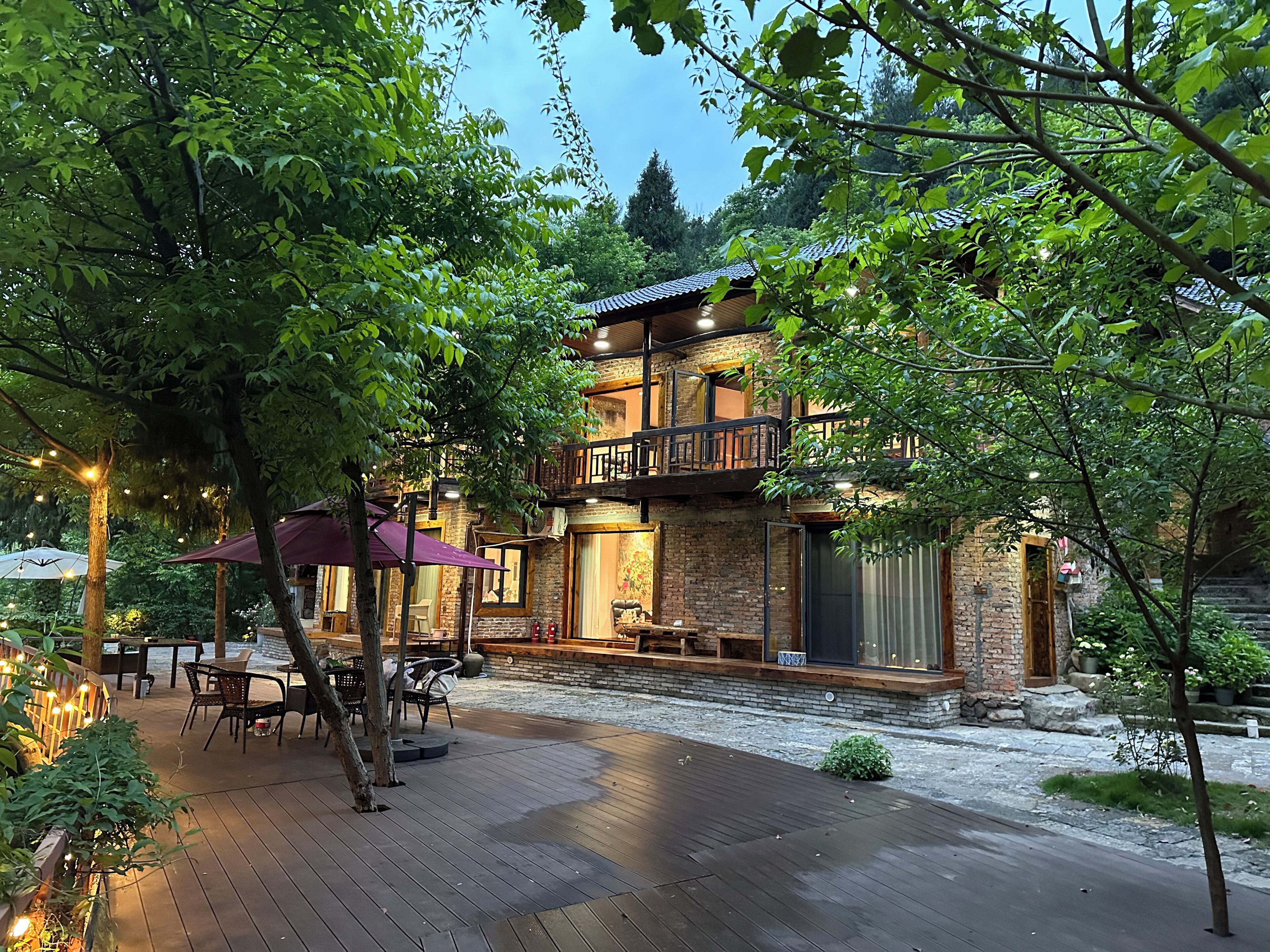 A two-story building with a balcony, outdoor seating, and a brick facade.