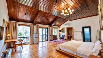 A spacious bedroom with a large bed, wooden flooring, and a sloped ceiling.