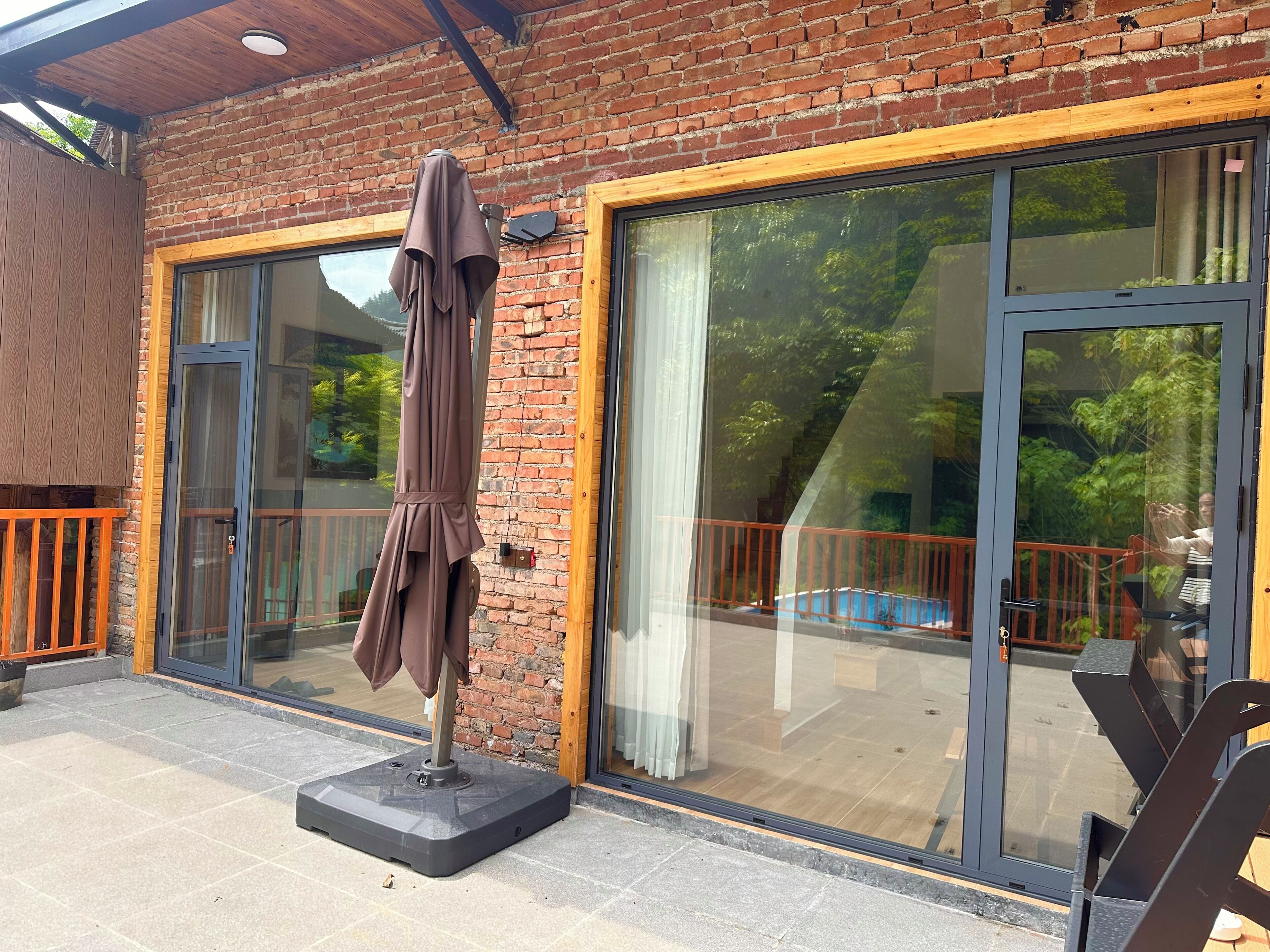 A patio area with a brick wall, large sliding glass doors, and a covered seating area with a table and chairs.