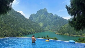 Una piscina con vista su un lago e montagne boscose.