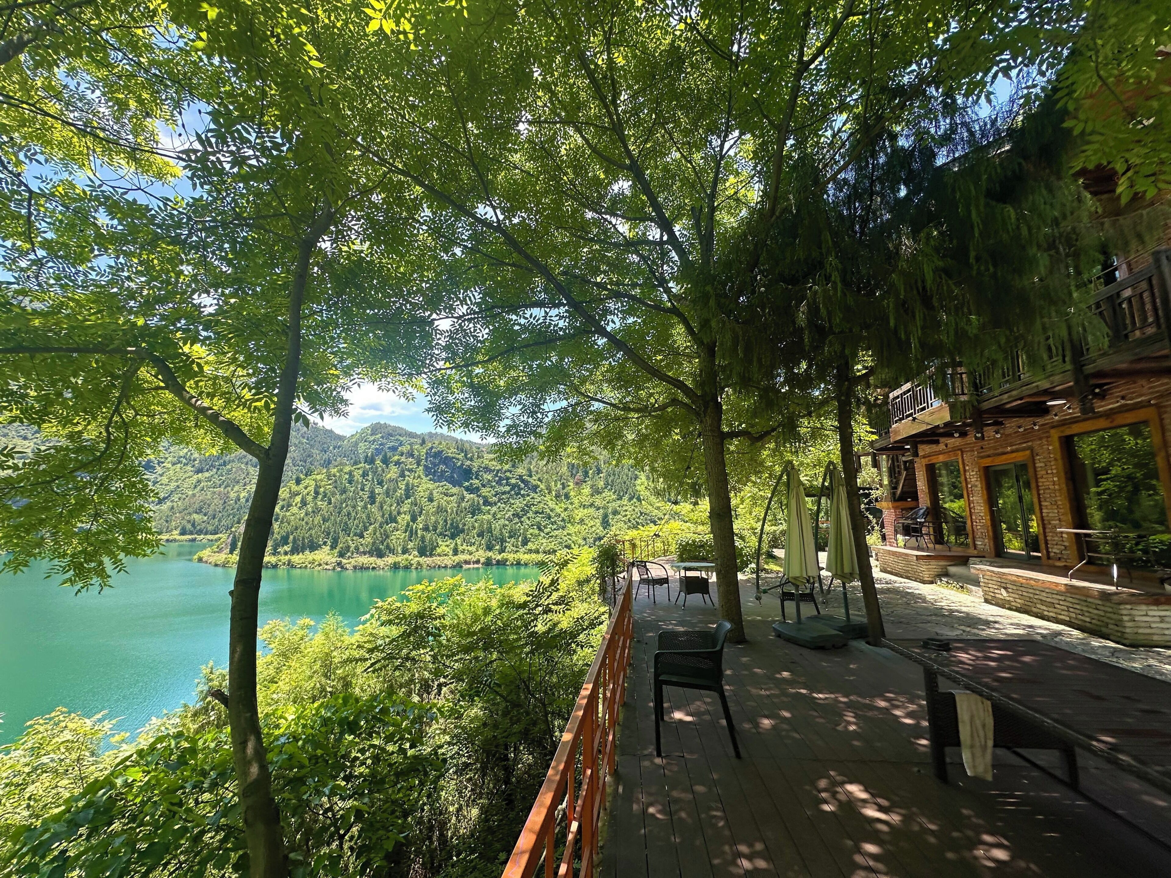 Terraza de madera con vistas a un lago y una colina boscosa.