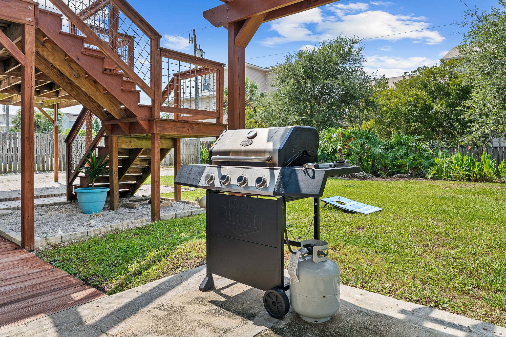 An outdoor grill setup with a gas tank, a control panel, and a chimney.