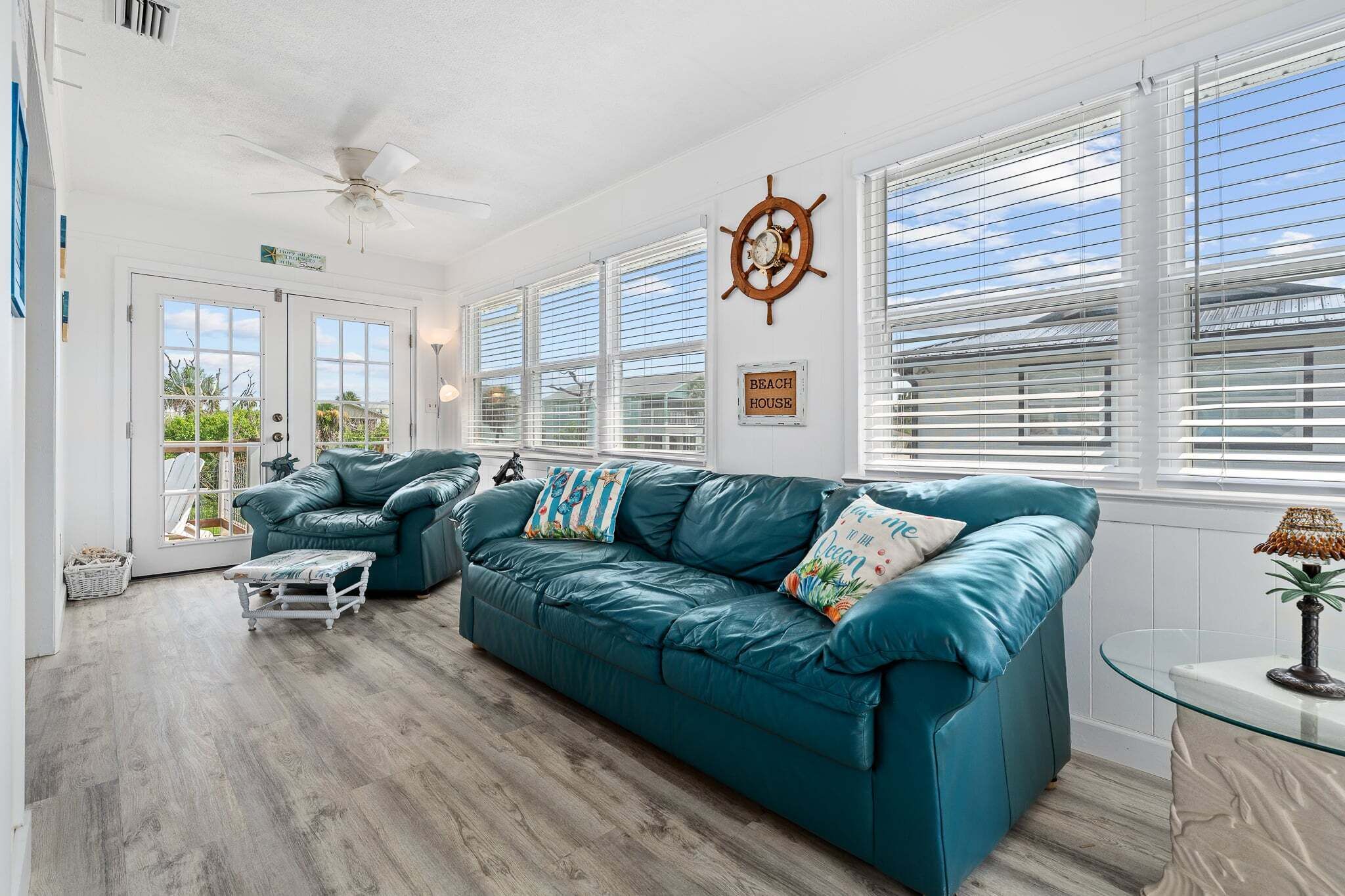 A spacious living room with a teal sofa, a coffee table, and a sail wheel decoration.