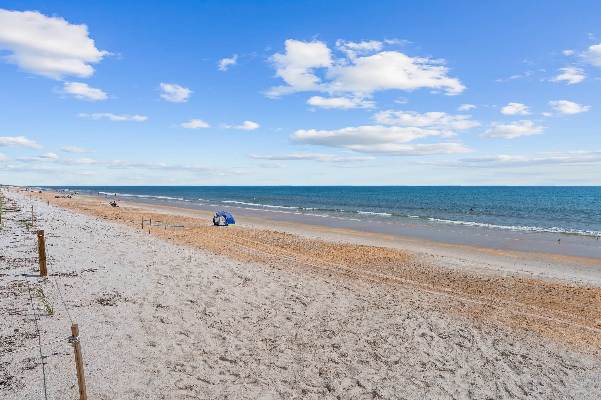 Ein Strand mit einem Zelt und einem Zaun.