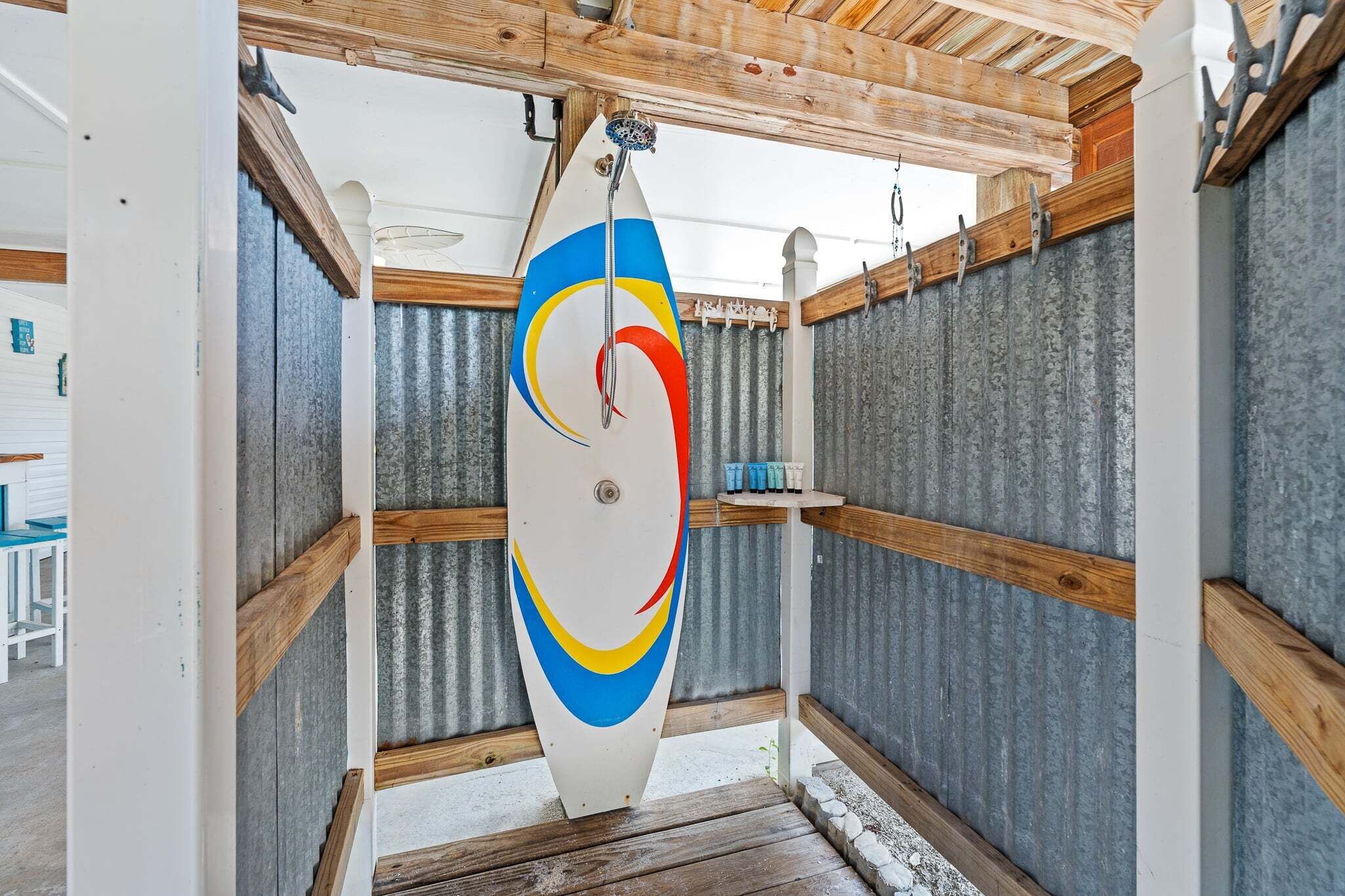 Ein kleiner, abgeschlossener Raum mit einem an der Decke hängenden Surfbrett, Holzbalken und einer Wand aus Wellblech.
