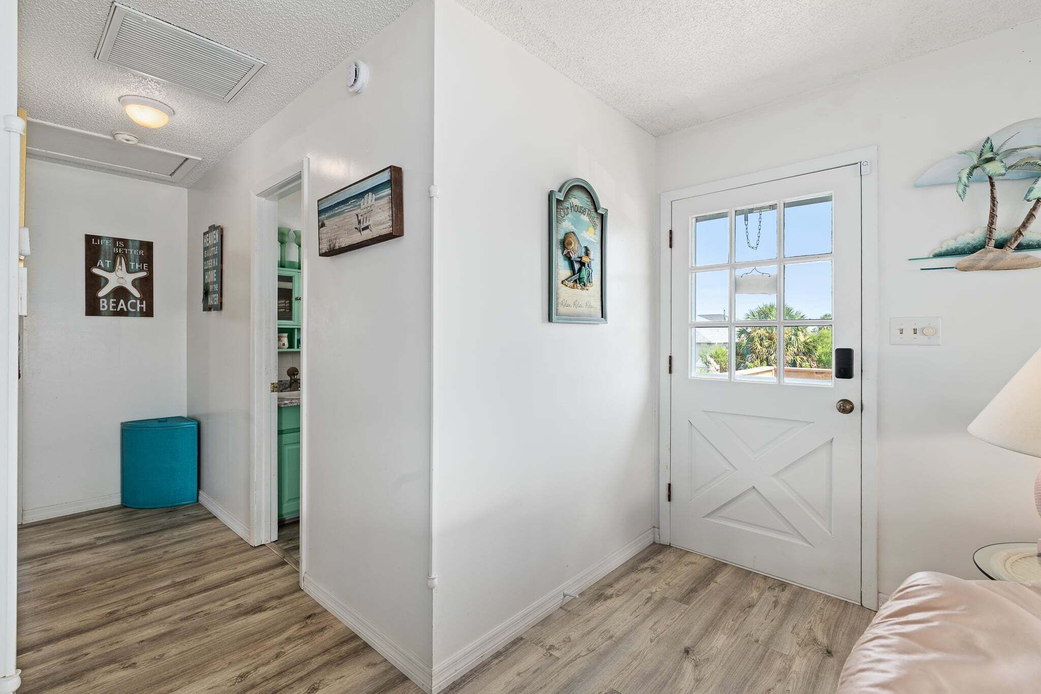 A hallway with a white door, a window with a view, and a doorbell.