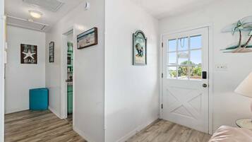 A hallway with a white door, a window with a view, and a doorbell.