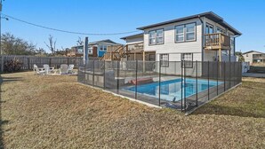 A residential property with a swimming pool, fenced yard, and a two-story house.