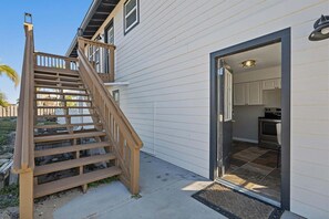 A wooden staircase leading to a house with a kitchen visible through an open door.