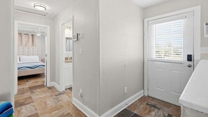 A hotel room with a bed, a bathroom, and a door leading to another room.