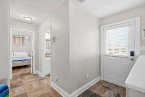 A hotel room with a bed, a bathroom, and a door leading to another room.