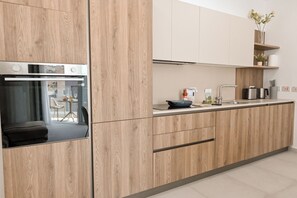 A modern kitchen with wooden cabinetry, a built-in oven, and a stainless steel range hood. - Modern Seaside Apart in Marsalforn - 5C, Marsalforn Iz-Zebbug Gozo, Malta (Marsalforn Iz-Zebbug Gozo)