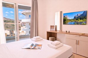 Une chambre d’hôtel avec un lit, un magazine, une télévision et une fenêtre donnant sur un paysage montagneux.