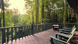 A wooden deck with benches and a table, surrounded by trees. - Peak Retreat at Rumbling Bald (Lake Lure)