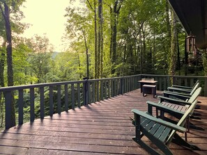 Eine Holzterrasse mit Bänken und einem Tisch, umgeben von Bäumen.