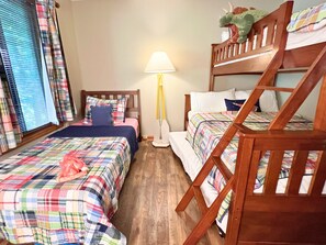 Ein Zimmer mit zwei Betten, einem Nachttisch, einer Lampe und einem Fenster mit Jalousien.