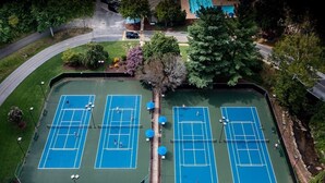A tennis court complex with multiple courts, surrounded by trees and a residential area. - Peak Retreat at Rumbling Bald (Lake Lure)