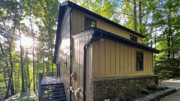 A wooden cabin with a stone foundation, surrounded by trees. - Peak Retreat at Rumbling Bald (Lake Lure)