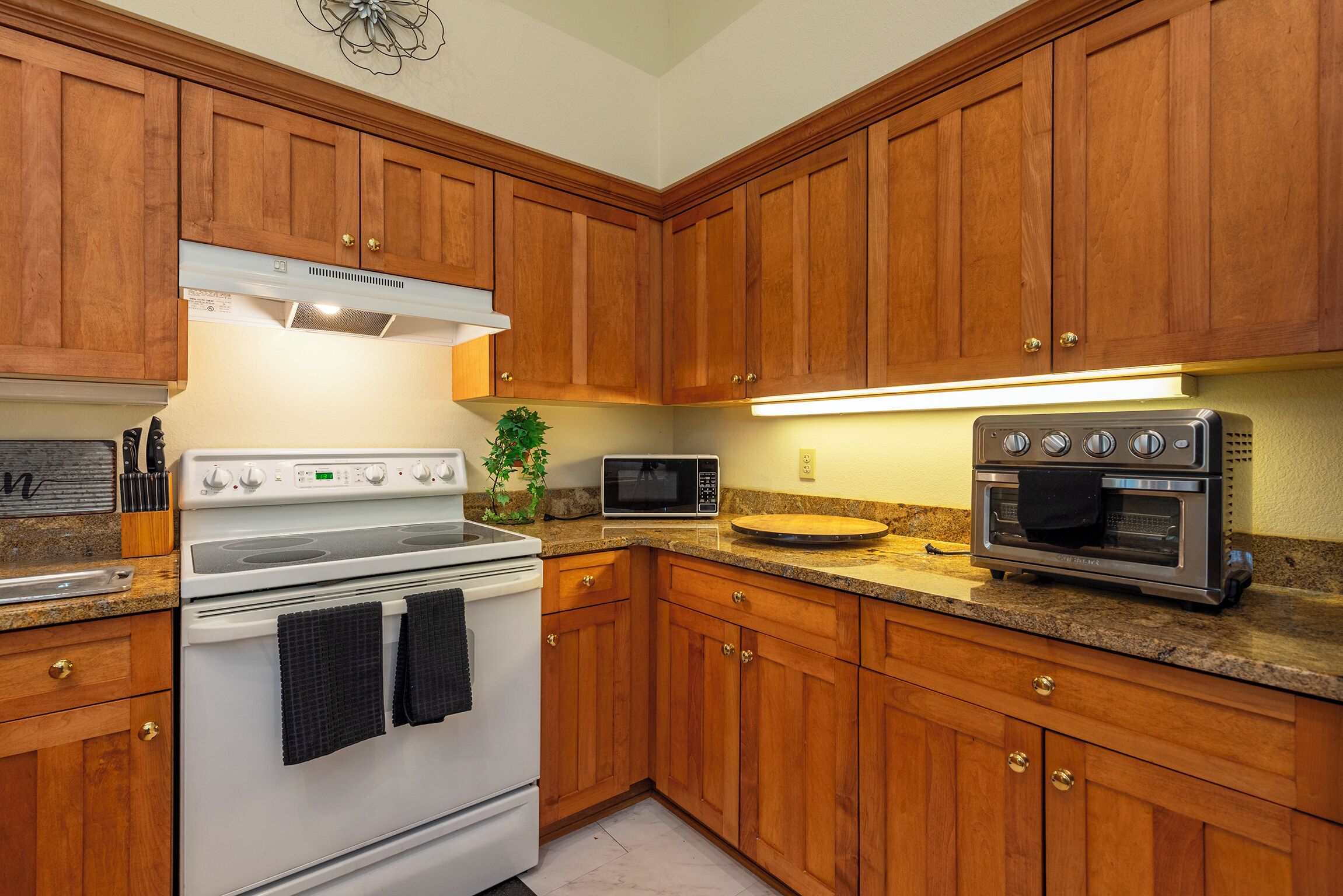 A kitchen with wooden cabinets, a white stove, a microwave, and an oven.