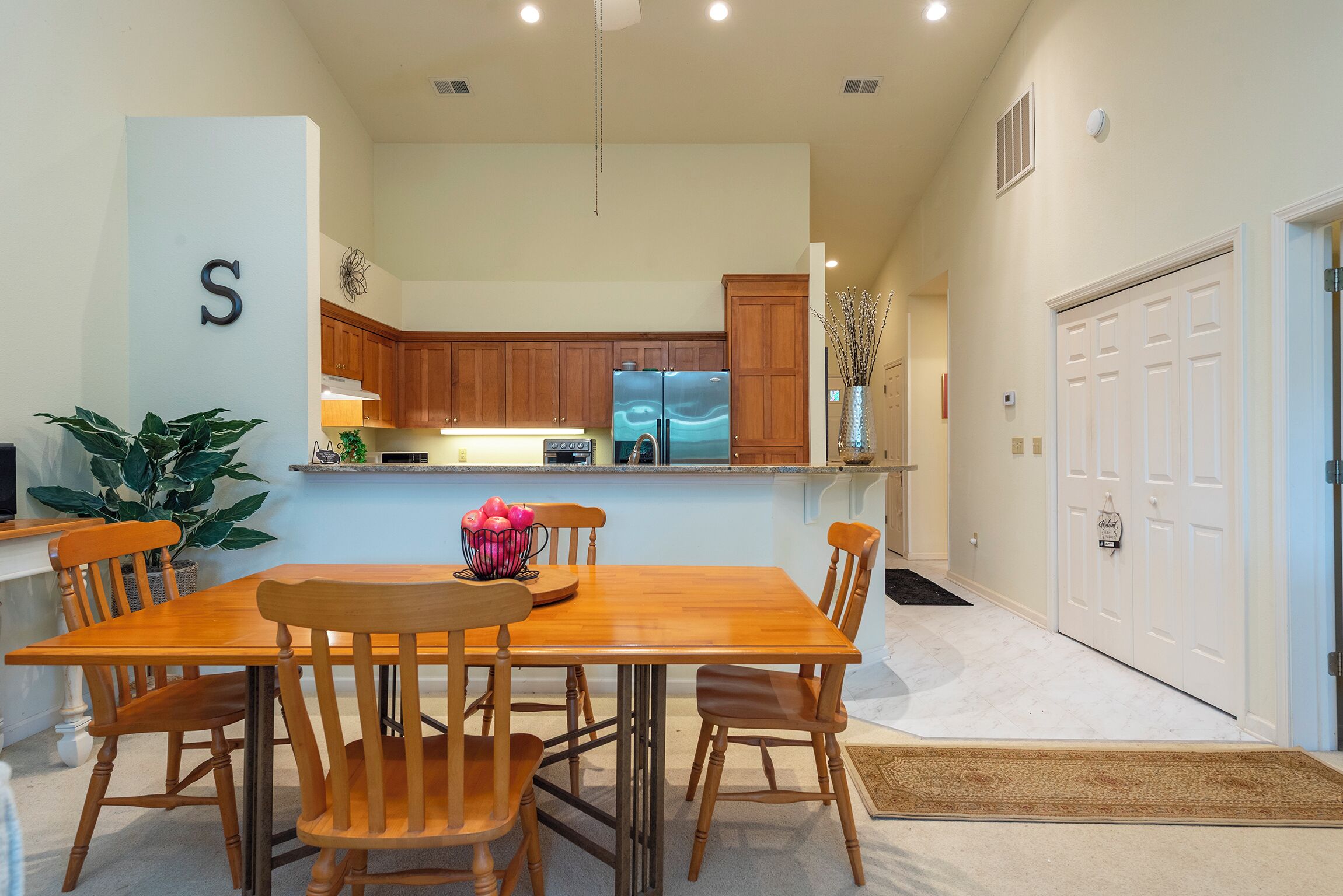 Una cocina moderna con armarios de madera, una isla central y un comedor con mesa y sillas de madera.