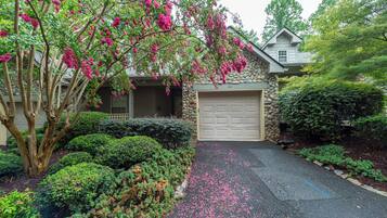 A residential property with a stone facade, a garage, and a driveway with scattered flower petals.
