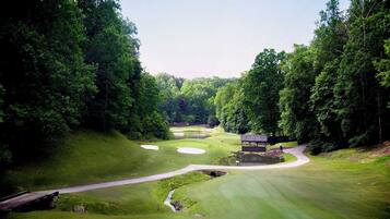 A golf course with a pond, a bridge, and a pavilion.
