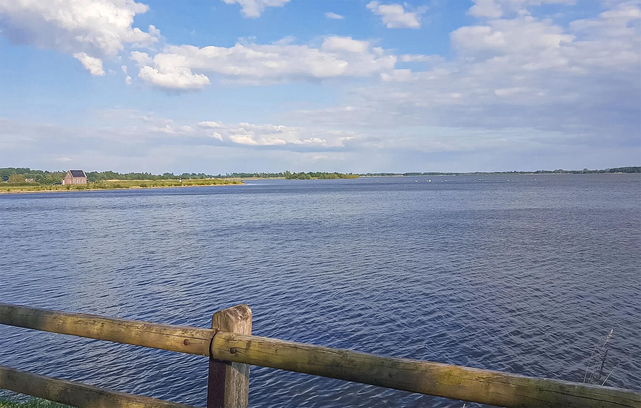 A calm body of water with a wooden fence in the foreground.