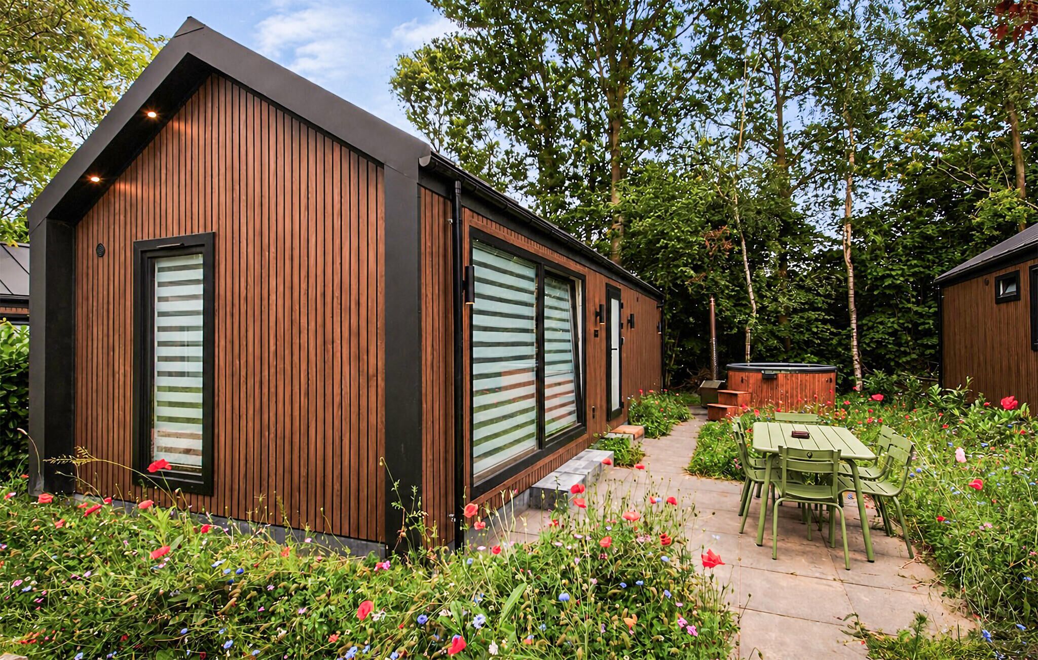 A modern wooden building with large windows and a patio area with outdoor furniture.